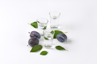 slivovitz (plum brandy) and fresh plums on white background